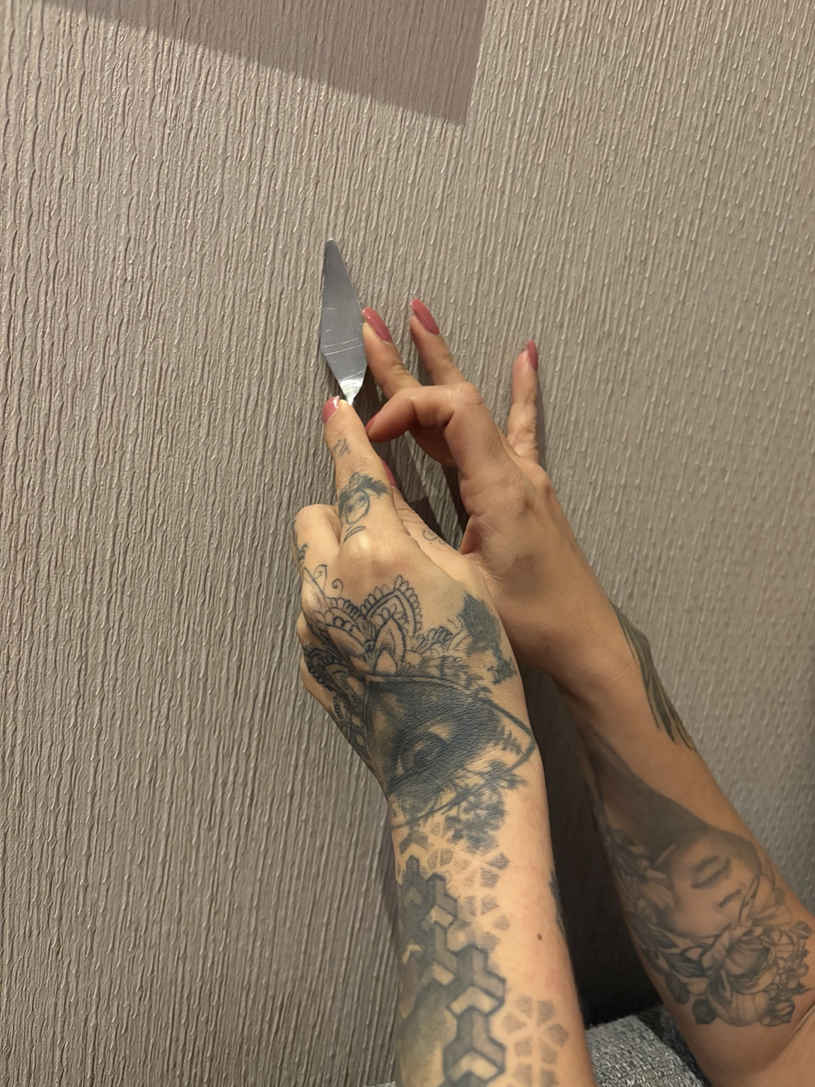 Aram’s tattooed hands and burgundy nails working with a palette knife