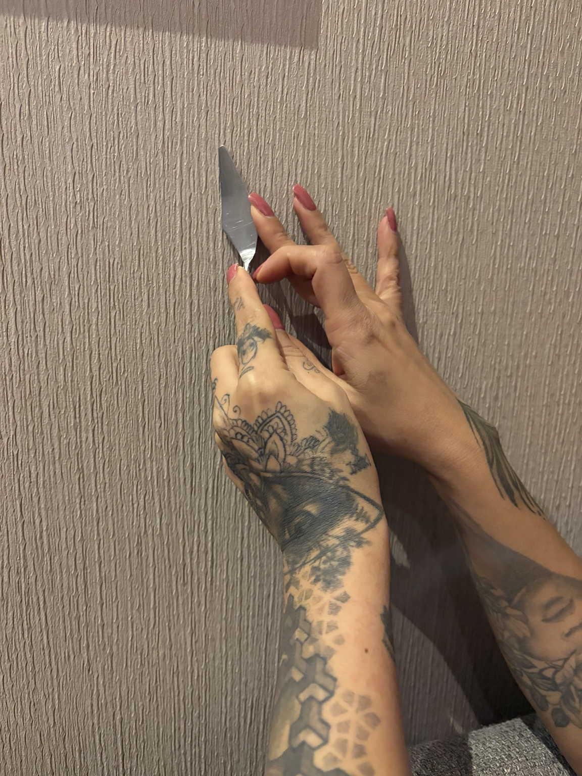 Aram holding a palette knife against textured plaster
